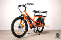 Vue de face d'un Vélo cargo longtail électrique Yuba Kombi Orange tout équipé