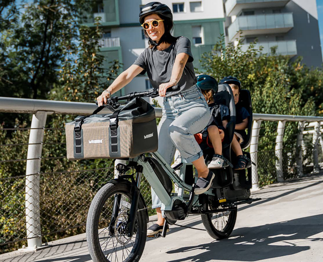 Femme sur un vélo cargo électrique avec deux enfants